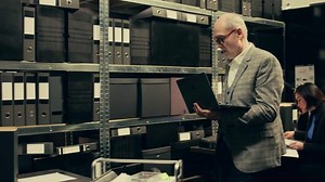 Private investigator searching for files based on case names in archive, looking for legal documents and classified information on laptop. Agent working on criminology in incident room. Camera B.