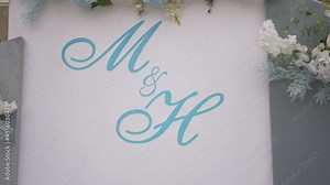 Wedding arch in the park among nature, trees, grass and flower beds. Wedding day. Preparation for the ceremony. Floral arrangements adorn the arch. The letters "M" and "H" are written on the arch Stock Video