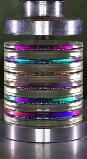 Nic Davis on Instagram: "A stack of rainbow-shifting dichroic glass lenses with glitter liquid between each layer gets crushed by a hydraulic press. As the press descends, the lenses shatter one by one, squeezing the sparkling liquid outward in mesmerizing concentric rings."