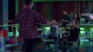 Friends playing and having fun at bowling HD slow-motion leisure video. Group of young man and woman at bar table celebrates winning.