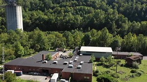 Aerial ascent over Marsh Fork Elementary School showing the Montcoal mining operation with slurry ponds and coal slurry pipelines in mountains of West Virginia.