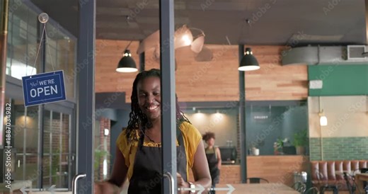 African American female baristas in aprons flipping closed sign pulling doors entering cafe opening