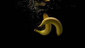 Premium stock video - Two fresh mature bananas falling together in the clear water