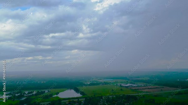 Expansive view of an overcast sky with distant rainfall spreading over rural fields. Ideal for themes of weather patterns, nature's vastness, or atmospheric changes in countryside settings.