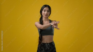 Ethnic woman Indian sporty girl sports trainer lady sport athlete female in yellow studio talk looking to camera explain exercise showing hand arm and neck head stretching pose stretch workout online