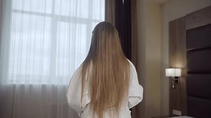 Woman removing bathrobe in hotel room