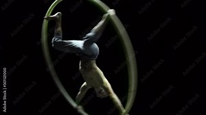 Muscular circus artist in the Cyr Wheel doing difficult tricks slow motion. Concept of concentration and balance