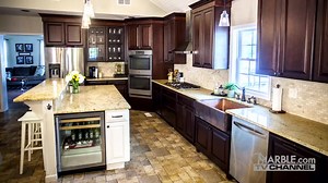Gold Madura granite kitchen countertops are a great choice to pair with dark brown cabinets. The stone floor pulls together the look of this rustic kitchen. | Marble.com