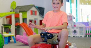 Boy driving a pedal car, child having fun riding a car in an amusement park
