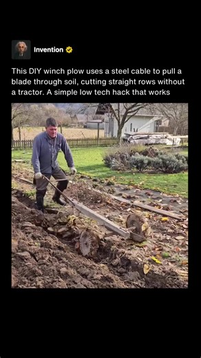 This device is a DIY cable winch plow designed to cut straight furrows in a garden bed without using a tractor or tiller. A steel cable is attached to the front of a lightweight plow frame and runs forward to a winch anchored off screen. As the winch reels in the cable, it pulls the plow steadily through the soil, allowing the blade to slice a clean, shallow groove for planting rows. The plow itself is built with a small cutting blade mounted between two spiked wheels. The wheels reduce friction
