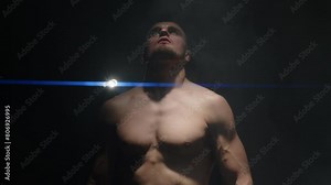 a bare-chested boxer looks up at the light and breathes. close-up