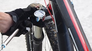 Pumping of the front, bicycle oil-air shock absorber using a specialized hand pump. Visible pressure. Top view. Active Lifestyle.