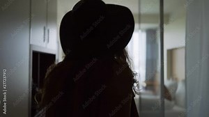 Back view woman opening door and entering in hotel apartment. Follow young pretty girl in hat moving room through dark hall, she happily smile . Concept of comfortable vacation Stock Video