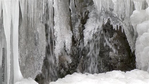 Many crowded icicles cover a natural frozen waterfall in cold air during winter. Winter conditions create dense ice formations as water freezes into clustered shapes.