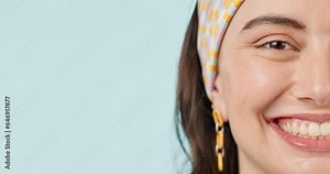 Half face, space and smile with a woman closeup on a blue background for marketing in studio. Portrait, mockup and a happy young person on a blank or empty banner for wellness advertising in studio