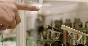 Close-up of customer finger pointing at vapes on display. Exploring selection of electronic cigarettes, considering various options for vaping devices, flavors, and features. Decision making process.