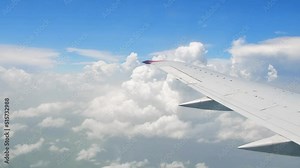 Window view boeing passenger jet plane wing with passing beautiful white cloud background. Travel and flying concept