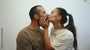 A young married couple in love tenderly kiss each other. The newlyweds kiss while sitting in their bedroom.