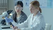 Technicien de laboratoire utilisant un microscope et communiquant les...