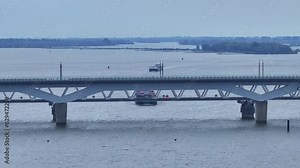 the Moerdijk bridges in Netherlands with cars moving and a ferry in passing underneath