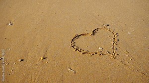 Heart symbol on the snad beach and sea waves.