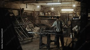 Painting ready-made metal forged products in the workshop using an electric sprayer. View from behind