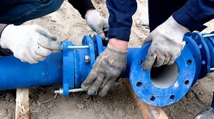 Workers installing water supply pipeline system, close up