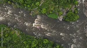 High above Drone aerial view on beautiful fast river with rapids and waterfalls. Extreme Rafting concept. Group of people on raft boat doing rafting on river.