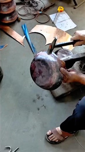 Hammering a heated metal sheet to shape it into a rounded vessel form