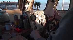 View inside of pilothouse with windows, compass, steering wheel, and dashboard. Clip. A man sailor leading its old and dirty ship.