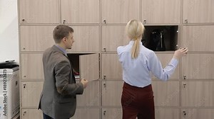 Man and woman open boxes and pick up things in modern office. Young managers taking personal belongings from cases and walking forward in company. Handsome guy and blonde in red skirt speak positively