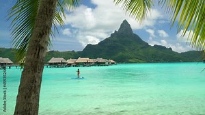 Tahiti beach vacation luxury resort hotel in Bora Bora, French Polynesia. Paddleboarding watersport leisure activity SUP paddle woman, French Polynesia. Mount Otemanu landscape