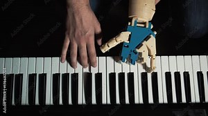 Robot plays a musical instrument. man musician pianist with a prosthetic hand playing the piano. He plays with two hands, a robot and a human hand. Robot creates music and art.