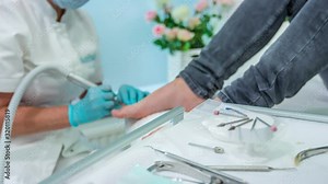Female pedicure specialist uses nail drill machine with pedicure tools in forefront