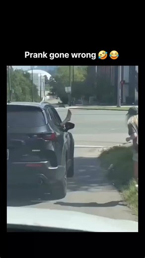 Viral on Instagram: "This video appears to be a staged prank depicting a supposed road rage incident and a subsequent confrontation. The video begins with an exterior shot of a dark grey SUV (Mazda CX-50) stopped on the side of a road, with a blonde woman in a cap, dark t-shirt, and jean shorts, leaning out of the passenger-side window to high-five someone’s extended hand sticking out of the window of the SUV. The woman then playfully jumps back and laughs. The scene immediately cuts to the inte