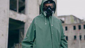 Human in radioactive green suit and gas mask. Guy wearing hazmat suit and gloves.