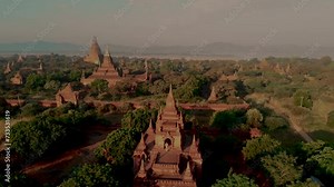 A couple visit the sunrise in Bagan Myanmar, drone aerial view sunrise with temples and old pagodas at the historical UNESCO site of old Bagan