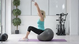 Happy healthy mature woman working out, falling off of fitness ball.