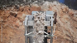 Quarrying of limestone in a quarry. Crushed stones pouring from conveyor on pile in a rock quarry. Quarrying stones with machinery. Mining company. Industry