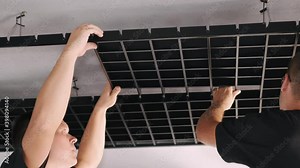 Open grid modern ceiling. Two professional workers are installing panels for metal open cell ceiling.