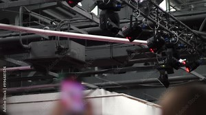 lighting equipment in front of the stage at a concert, the audience at the concert is out of focus, lighting fixtures illuminating the stage and the auditorium