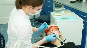 Close up female dentist hands in sterile gloves making treatment to patient using drill machine. Professional stomatologist in mask drilling teeth to female client. care, treatment. bur, tips