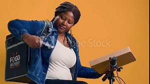 African american woman uses bicycle and digital POS machine to ensure contact-free delivery service. Female bike messenger offering nfc terminal for easy wireless payment for meal delivery.