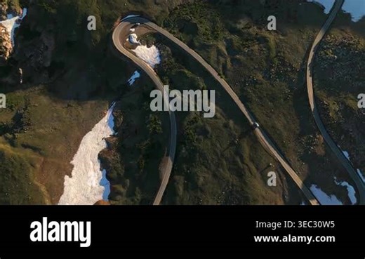 Beartooth Highway in Montana curves dramatically through rugged alpine landscape with melting snow patches. Aerial view captures cars navigating the serpentine road at golden hour Stock Video Footage - Alamy