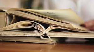 Close-up opened book on the table in library. Blurry bookshelf background for education and publication concept. Back to school. Bookshelves in school study class room background.