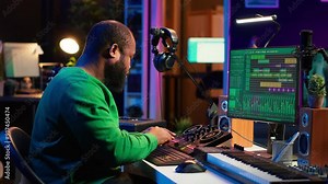 African american composer creating a new track for a project, using professional production pc interface in his home studio. Creative artist songwriter producing music with sound effects. Camera A.