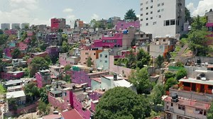 Drone flying above the vibrant slum district. 4K aerial over colorful pink low-income favelas in Mexico suburban. Poor people living view. Green latin town in Mexico city. 4K aerial Central America