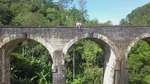 Tourist couple sit on edge of Nine Arches railway bridge in Sri Lanka