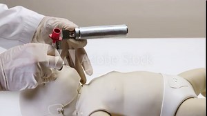 A doctor practice inserting a neonatal laryngoscope with a newborn mannequin.