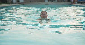 Athlete Young Woman Swims in Swimming Pool at Luxury Hotel Spa and Enjoying Beautiful Sunset